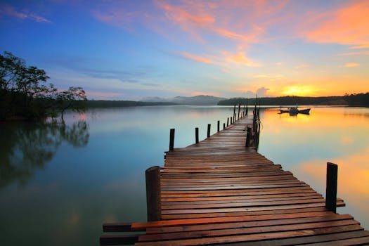 Réflexologie Serene sunset view over a tranquil lake with a wooden dock stretching into the distance.