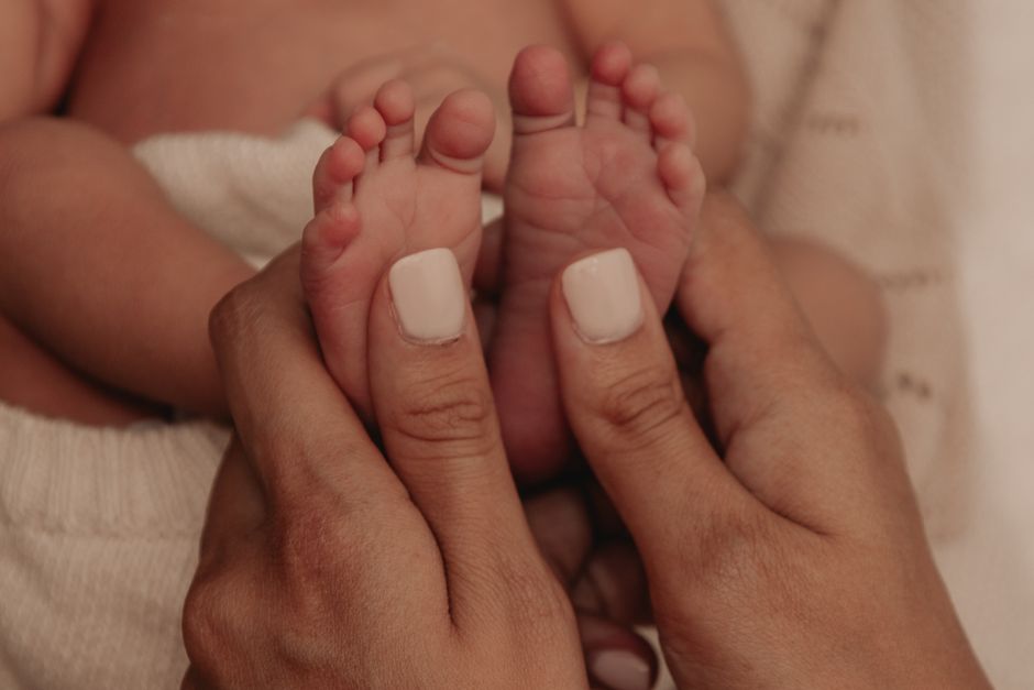 Tender close-up shot of mother gently holding her newborn's feet, symbolizing love and care.