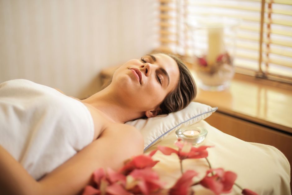 Réflexologie Woman enjoying a relaxing spa day with flowers and candles indoors.