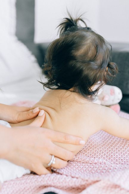 A gentle massage being given to a baby on a soft blanket, promoting relaxation.